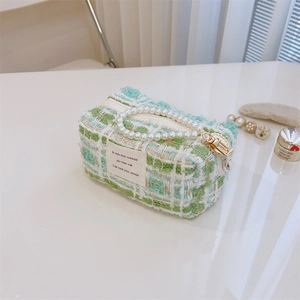Detail of green and white tweed handbag with faux pearl handle and gold zipper charm