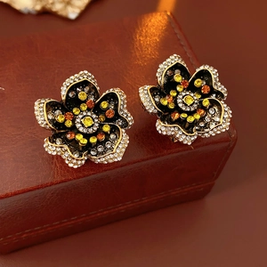 Macro detail of vintage gold flower earrings with colorful rhinestones on a brown box