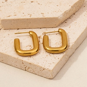 Detail of gold U-shaped 304 stainless steel earrings on beige travertine stone display