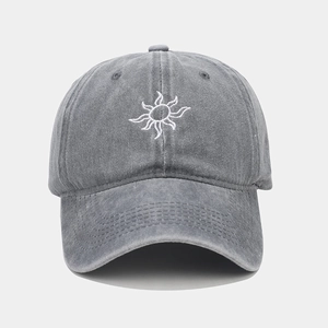 Close-up of vintage sun embroidery detail on washed grey cotton baseball cap texture