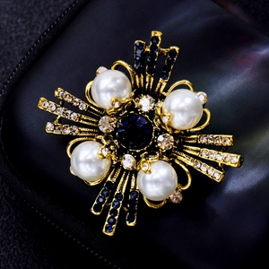 Detail showing vintage gold brooch with large pearls, blue sapphire, and rhinestones