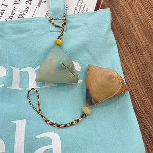Close-up of triangular fabric rice dumpling charms in green and yellow with woven cords