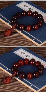 Close-up of deep red sandalwood prayer beads with a carved Buddha pendant on vintage books