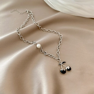 Detail of silver chain necklace with a white pearl and black cherry pendants on silk