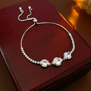 Macro detail of silver adjustable bracelet with oval zircons on red wooden box