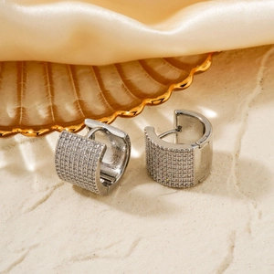 Elegant silver micro-pave zircon hoop earrings on a textured surface with golden glass tray