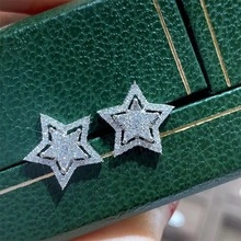 Close-up of sparkling silver star stud earrings on premium green leather jewelry box