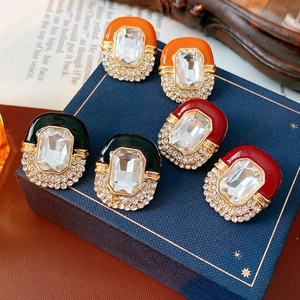 Detail of vintage enamel oval earrings with crystal rhinestones in orange, green, and red