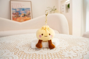 Close-up of a cute plush bun keychain with embroidery detail on a white lace tablecloth