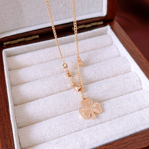 Detailed view of a gold clover pendant with 520 engraving on a beaded chain necklace