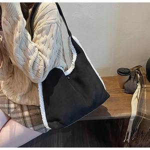 Detail of large black suede tote with fleece trim on a model in a cafe setting
