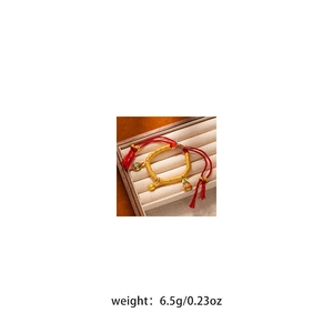 Macro detail of red woven bracelet with gold-tone gourds and 6.5g weight specification