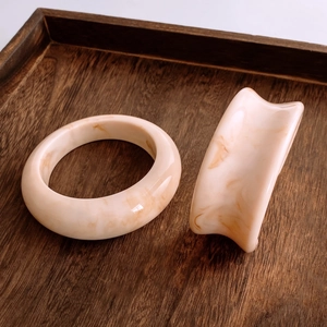 Vista dettagliata di bracciali minimalisti in resina con trama marmorea su vassoio in legno