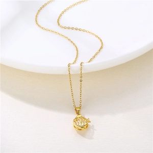 Minimalist gold stainless steel necklace with hollow spherical pendant on a white plate