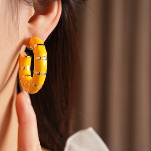 Close-up of a vintage yellow enamel C-shaped earring on a model for a stylish look