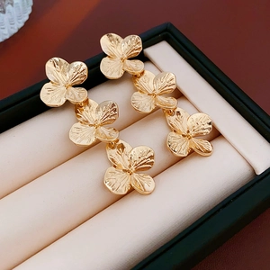 Macro shot of gold floral earrings with three connected flowers in a jewelry box