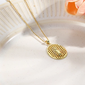 Detail of gold oval Virgin Mary pendant with honeycomb cutout design on ceramic tray