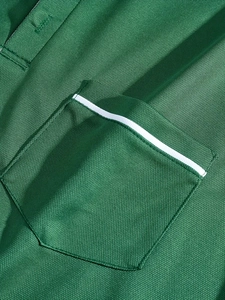 Macro de la textura del polo verde que muestra el tejido de malla y detalle del bolsillo