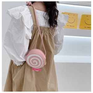 Pink lollipop shaped crossbody bag with spiral pattern and bow detail on a young girl