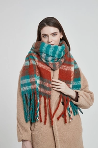 Detail of teal and rust red plaid scarf featuring long tassels and thick fuzzy texture