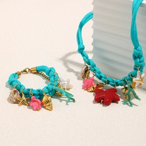 Detailed view of ocean themed blue braided rope necklace and bracelet with marine charms