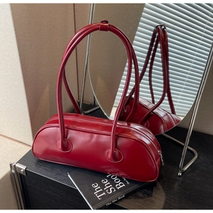 Detailed shot of burgundy faux leather bowling bag with long handles on a stylish prop