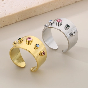 Detail of wide brushed titanium steel rings with colorful zircons in gold and silver