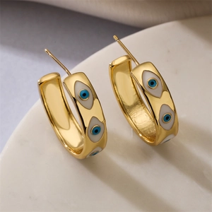 Close-up of gold-plated hoop earrings featuring blue and white enamel evil eye patterns
