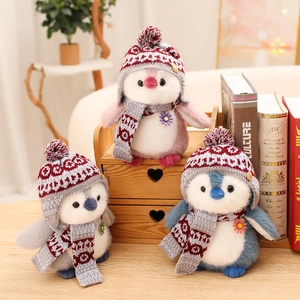 Three plush penguin dolls wearing knitted hats and scarves arranged on a wooden shelf