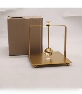 Detail of a Nordic golden napkin holder with crystal top and square base beside packaging