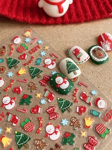 Close-up of Christmas nail art stickers featuring 5D embossed trees and snowman patterns