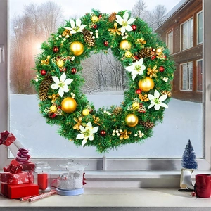 Christmas wreath with green needles, golden ornaments and red berries on a snowy window