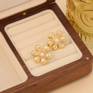 Detail shot of gold flower earrings with white pearl centers in a luxury walnut box