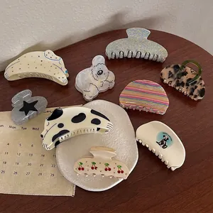 Collection of acetate claw clips with cherry prints and animal patterns on a wooden table