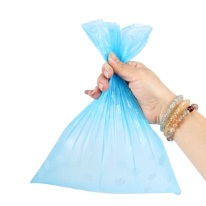 Blue biodegradable pet waste bag with paw prints shown in hand for size and durability