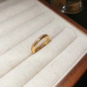 Detailed close-up of 18k gold plated ring with micro-paved zircons in a beige jewelry box