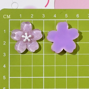 Macro detail of cherry blossom resin charms with purple glitter finish and size scale