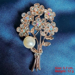 Detail of rose gold flower bouquet brooch with sparkling crystals and a large pearl