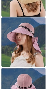 Detail view of pink sun hat with wide brim, striped ribbon, and large neck bow