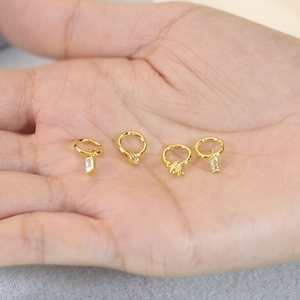 Golden S925 sterling silver hoop earrings with diamond charms displayed on a hand