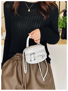 Detail of white quilted mini handbag with woven chain strap and dual zipper closure