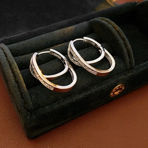 Macro detail of silver double-layered crisscross hoop earrings with sparkling zircons