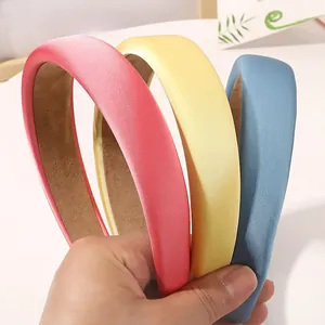 Close-up of three colorful padded sponge headbands in pink, yellow, and blue satin