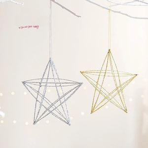 Glittery metal star Christmas ornaments in gold and silver hanging on a festive tree branch