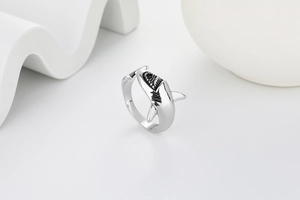 Macro shot of silver shark ring detail with black enamel accents on white pedestal