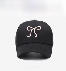 Vue de face d'une casquette de baseball noire avec broderie nœud rose et visière