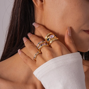 Set of 6 gold rings with pink and blue rhinestones worn by a model in a stacked style