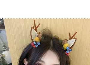 Detailed close-up of a Christmas reindeer antler hair clip with berries and pine cones