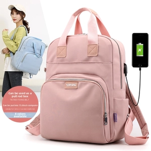 Pink nylon backpack detail showing luggage strap and external USB charging port