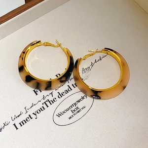 Close-up of leopard print acetate hoop earrings with elegant gold metal accents